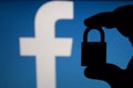 Tula, Russia - August 28, 2018: Facebook security issues. Silhouette of a hand holding a padlock infront .