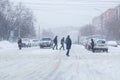 Tula, Russia - February 13, 2020: Citizens crossing city road during heavy snow fall.