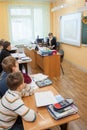 Tula, Russia - January 18, 2013: Young teacher woman sitting at the table in front of student boys in a middle school Royalty Free Stock Photo