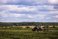 TULA, RUSSIA - JULY 30, 2019: green haymaking tractor on summer field before storm - telephoto shot with selective focus