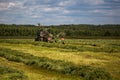 TULA, RUSSIA - JULY 30, 2019: green haymaking tractor on summer field before storm - telephoto shot with selective focus