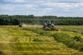 TULA, RUSSIA - JULY 30, 2019: green haymaking tractor on summer field before storm - telephoto shot with selective focus