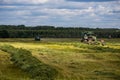 TULA, RUSSIA - JULY 30, 2019: green haymaking tractor on summer field before storm - telephoto shot with selective focus