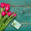 Tulip bouquet and small gift box on green wooden background Royalty Free Stock Photo