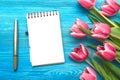 Tulip flowers and blank note pad paper page on wooden background with copy space. Woman day concept. Romantic background. Royalty Free Stock Photo