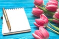 Tulip flowers and blank note pad paper page on wooden background with copy space. Woman day concept. Romantic background. Royalty Free Stock Photo