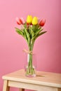 Tulip flowers bouquet for celebration on pink background. Artificial tulips arrangement in vase