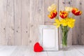 Tulip flowers for Mother`s Day greeting in glass vase over wooden table and wall Royalty Free Stock Photo