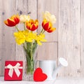 Tulip flowers for Mother`s Day greeting in glass vase over wooden table and wall Royalty Free Stock Photo