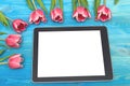 Tulip flowers and tablet computer device with blank screen on wooden background with copy space. Woman day concept. Royalty Free Stock Photo