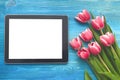 Tulip flowers and tablet computer device with blank screen on wooden background with copy space. Woman day concept. Royalty Free Stock Photo