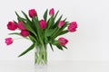 Tulip flowers in a transparent small vase standing on white table