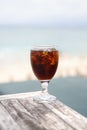 Tulip glass with cola on table. Beach umbrellas on the background Royalty Free Stock Photo