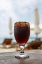 Tulip glass with cola on table. Beach umbrellas on the background Royalty Free Stock Photo