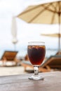 Tulip glass with cola on table. Beach umbrellas on the background Royalty Free Stock Photo