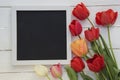 Tulips with blank black chalkboard picture frame on white wooden background. romantic picture. Royalty Free Stock Photo