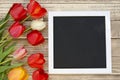 Tulips with blank black chalkboard picture frame on a wooden background. romantic picture. Royalty Free Stock Photo