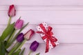 Tulips bouquet and gift box on white wooden background. Copy space. Spring banner Royalty Free Stock Photo