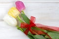 A tulips bouquet with red ribbon on a white wooden background Royalty Free Stock Photo