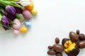 Tulips, chocolate Easter eggs and duck on white wooden background. Flat lay. Top view Royalty Free Stock Photo