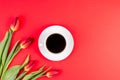 Tulips and cup of coffee on red background. Flat lay, top view. Royalty Free Stock Photo
