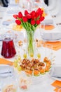 tulips on festive table. serving table with appetizers, canapes, salads in jars Royalty Free Stock Photo