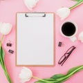 Tulips flower with mug of coffee, clipboard and glasses on pink background. Blogger or freelancer concept. Flat lay, top view.