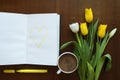 Tulips and heart in a book on a wooden table Royalty Free Stock Photo