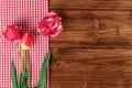 Tulips with red checkered tablecloth on country wooden background. Top view, text space
