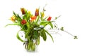 Tulips in red and yellow with spring branches as a bouquet in a glass vase isolated with small shadows on a white background,