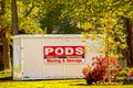 PODS moving-storage container sitting beside house in residential neighborhood surrounded by spring trees