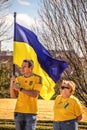 Young man holding Ukrainian flag and older woman in blue jeans and yellow tee-shirts at rally to Royalty Free Stock Photo