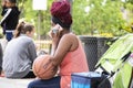 Black woman with red braids sits at the Gathering Place holding a basketball and talking on a pink phone