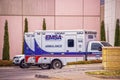 .EMSA Emergency Ambulance Paramedic Vans parked in front of pink stucco hospital with cypress tree