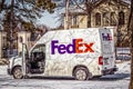 Fed Ex delivery truck parked on snowing road in front of blurred luxury mansion with high fence - door to Royalty Free Stock Photo