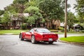 Red Corvette preparing to turn at intersection in residential neighborhood in summer Royalty Free Stock Photo