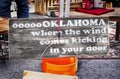 Tulsa USA - Rustic wooden sign sitting on a bucket that reads oooooOKlahoma where the wind comes kicking in the door