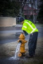 1-29-2019 Tulsa USA Waste and Sewer Worker turning off the water on a yellow fire hydrant near a wet street with two story house