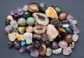 Tumbled and rough gemstones and crystals of various colors on  a grey background. Amethyst, geode amethyst, rose quartz, agate, Royalty Free Stock Photo