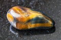 tumbled tiger-eye and hawk-eye gemstone on dark Royalty Free Stock Photo