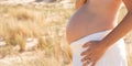 Tummy pregnant woman standing outdoor sand dune beach with pregnancy belly