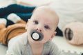 Tummy time. Cute newborn baby with big blue eyes and pacifier looking at camera Royalty Free Stock Photo