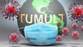 Tumult and covid - Earth globe protected with a blue mask against attacking corona viruses to show the relation between Tumult and Royalty Free Stock Photo