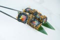 Tuna Black rice Sushi roll with cattle fish inks in chopsticks. Roll pieces with salmon, rockfish, cucumber and tuna chips Royalty Free Stock Photo