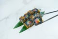 Tuna Black rice Sushi roll with cattle fish inks in chopsticks. Roll pieces with salmon, rockfish, cucumber and tuna chips Royalty Free Stock Photo