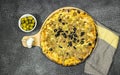 tuna pizza with cheese and tomato and olives on cutting wooden board with green olive bowl and garlic Royalty Free Stock Photo