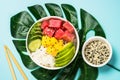 Tuna poke bowl with rice, avocado, mango and cucumber on blue. Royalty Free Stock Photo