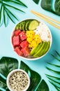 Tuna poke bowl with rice, avocado, mango and cucumber on blue. Royalty Free Stock Photo