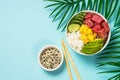 Tuna poke bowl with rice, avocado, mango and cucumber on blue. Royalty Free Stock Photo