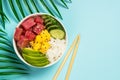 Tuna poke bowl with rice, avocado, mango and cucumber on blue. Royalty Free Stock Photo